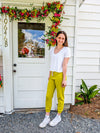 Showing Alyssa standing outside of the store, full body picture. Wearing white Frankie V-neck short sleeve shirt with Keziah Lime Joggers.